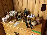 Overview of all items on wooden shelf including teapot set, figurines, fans, salt and pepper shakers, tiki cup, wooden egg, and brass key