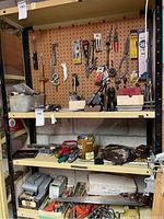 Full view of all three shelves with various tools including hand saw, vises, screwdrivers, power drill, clamps, and small accessories.