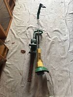 Black & Decker electric hedge trimmer with long toothed blade and green handle alongside the weed trimmer.