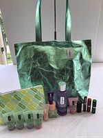 Metallic green Clinique tote bag, assorted small skincare and makeup bottles and tubes, and the patterned makeup pouch visible in the background.