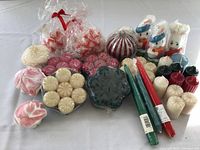 Full view of assortment of votive candles in various shapes and colors, some wrapped and some loose