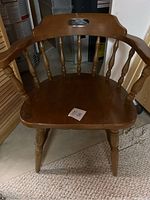 Front view of wooden captain's chair showing seat, armrests, turned legs and backrest spindles.