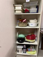 Open cupboard showing shelves stacked with various Tupperware containers, Corning Ware cookware, and colorful plastic bowls.