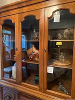 Wide view of cabinet contents showing multiple decorative and glassware items inside wooden cabinet with glass doors.
