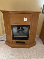 Front view of the freestanding electric fireplace heater with wood-finish, showing fire viewing window and side cabinets closed.