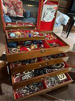 View of the open wooden Asian-themed jewellery box showing multiple drawers filled with assorted costume and silver jewellery pieces.