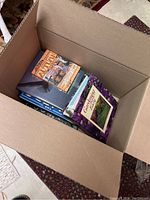 Box containing a collection of gardening and nature books, showing multiple book spines and covers including a prominent autumn book.