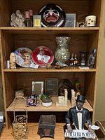 Wooden shelves displaying assorted knick knacks including figurines, decorative plates, glassware and photo frames