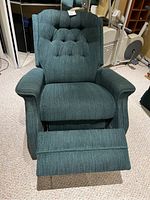 Front view of the green upholstered recliner chair with footrest extended showing tufted backrest and cushioned armrests.