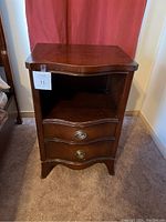 Front view of one bedside table showing two drawers and one open shelf, dark brown wood with brass drawer pulls.