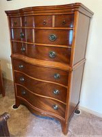 Front view of the tall boy dresser showing curved drawer fronts and metal oval drawer pulls in Eastlake style.