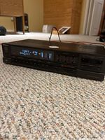 Front angled view of the Technics stereo amplifier on carpet showing digital display with tuner frequency, volume bars, and graphic equalizer sliders.