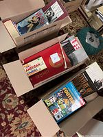 Open boxes filled with various large hardback coffee table books on cinema, Hollywood, and sports themes