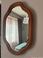 Front view of wood framed oval mirror showing curved wooden frame and clear reflective surface