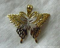 Front view of butterfly pendant showing yellow and white gold details and attached bail.