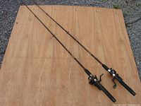 Photo of two assembled fishing rods with reels placed on wood surface, showing overall condition and setup.