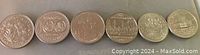 Photo showing six Canadian one dollar coins with different commemorative designs arranged side by side.