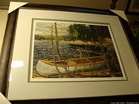 Photo showing the framed print of a canoe in a natural setting by Tom Thomson.