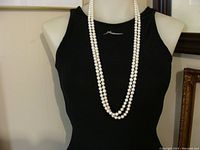 Necklace draped on mannequin bust wearing black top showing full length style when worn