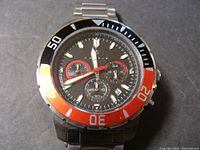Front view of Nautis dive watch showing black dial with three chronograph subdials, date window, and red-and-black rotating bezel.