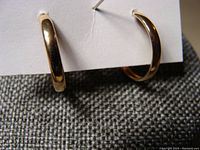 Front view of small gold hoop earrings showing smooth polished finish and 10K marking.