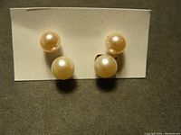 Photo of two pairs of pearl stud earrings on white backing card.