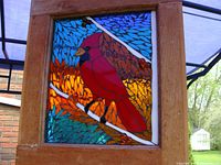 Frontal view of stained glass cardinal artwork framed in natural wood.