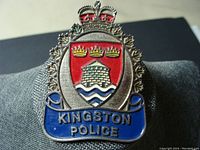 Front view of the vintage Kingston Police metal badge, showing colored enamel shield with crown and text details.