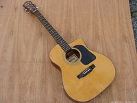 Full front view of the acoustic guitar showing wood finish, cutaway body, and pickguard.