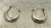 Photo showing the front view of the two vintage sterling silver hoop earrings with rounded hoop shape and hinged latch closures.