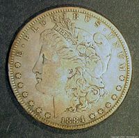 Obverse side of 1884 Morgan Silver Dollar showing Lady Liberty head in profile, date 1884, and E PLURIBUS UNUM inscription.