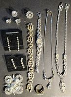 Full display of the jewelry set on black background showing earrings, bracelets, watch, ring, necklaces and brooch.