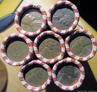 Seven rolls of wheat pennies viewed from the top with visible Lincoln heads on the obverse of the pennies.