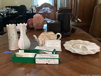 Photo shows entire lot on a wooden table including two Belleek vases, one with visible damage, Lenox Irish Blessing teapot, two boxed Irish clay pipes, and a Lenox deviled egg dish.