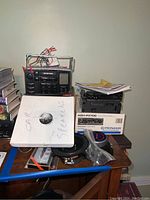 Photo showing Toyota car stereo, Pioneer KEH-P3700 box, two sets of speakers, and miscellaneous items on a wooden surface.
