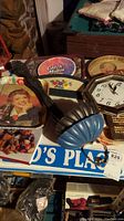 Photo showing Coca-Cola tray, Catch Minton tray, Old Dutch Beer tray, blue decorative fan, clock, and metal holders on a table.