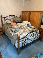 Full view of queen size bed with metal and wood headboard and footboard with mattress and bedding on top.