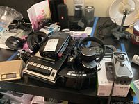 Top view showing various radios, tape recorder, headphones, and accessories on tabletop