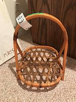 Front view of a basket made from a wooden snow shoe frame with woven base and decorative bindings.