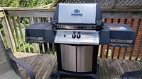 Full view of the Broil King Crown natural gas BBQ grill with side shelves and storage cabinet under grill.