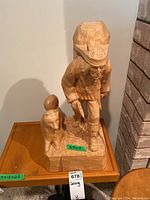 Front-angle view of the wood carving showing the man and his dog, detailing the full figure and base