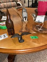 Four bird sculptures on table showing wood carved birds and metal bird statue with wings spread.