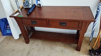 Front view of oak Mission style console table with two drawers and items on top.