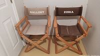 Two wooden director style chairs side by side, beige and brown fabric with names printed, showing fading and wear.