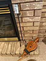 Fireplace tools displayed on fireplace hearth including poker and wooden bellows.