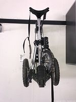 Folded golf cart showing all three wheels and compact frame storage design.