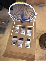 All six solar powered LED lights laid out on cardboard with the small metal basketball hoop behind them