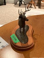 Full view of metal deer statuette on wooden base, showing overall shape and size
