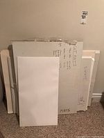 Stack of white and off-white mats with handwritten size notes on boards.
