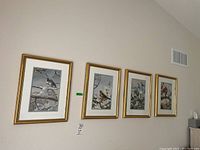 Four framed bird prints hanging on a wall, all in gold frames with cream mats and featuring birds on snowy branches.